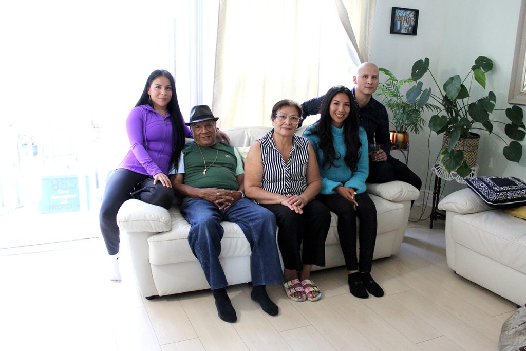 Habitat Partner Family Carlos and Eva sitting on a couch with three of their adult children in their Habitat home.