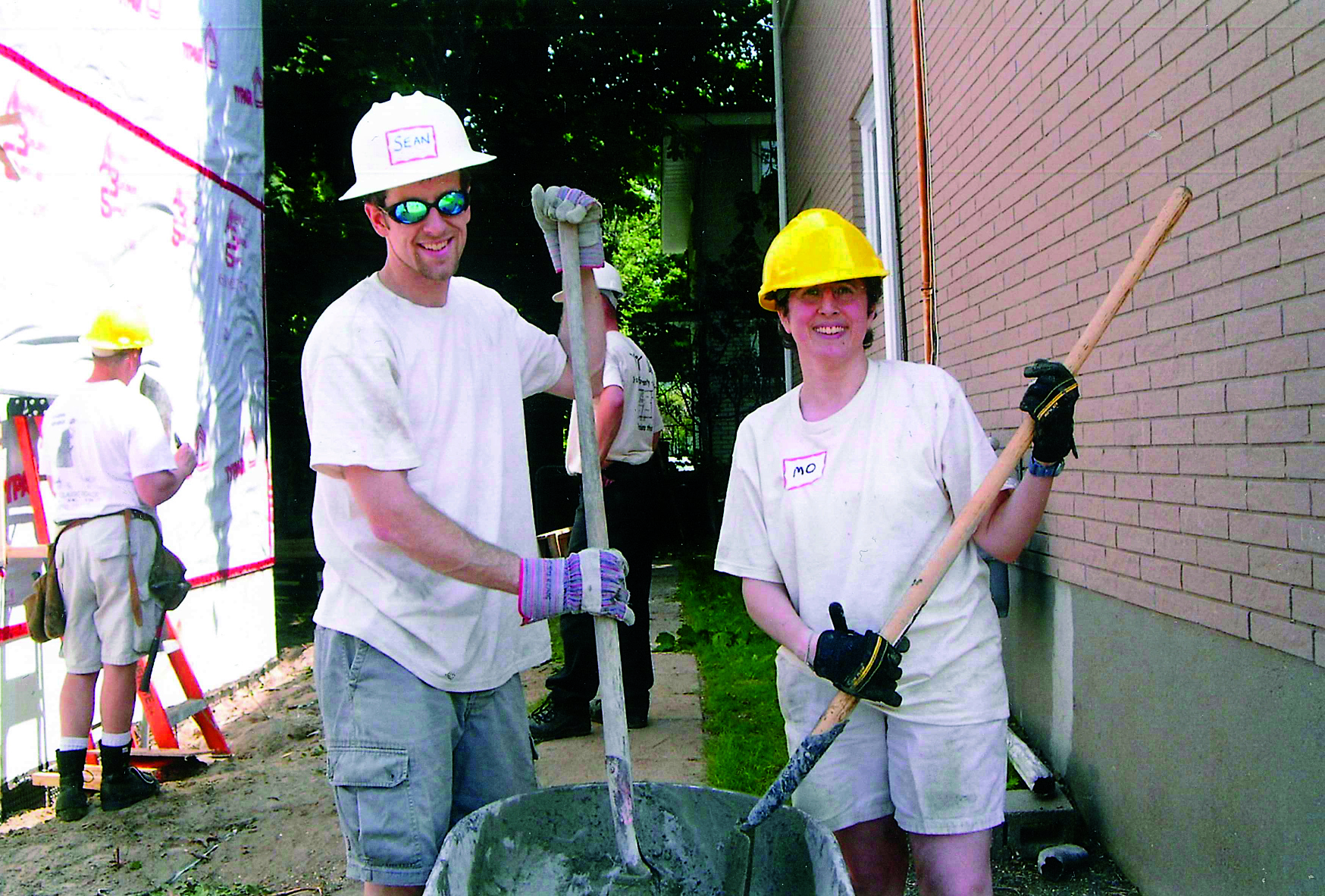 Two Habitat volunteers wearing construction had and holding shovels on site at Carlos and Eva's Habitat home in 2006.