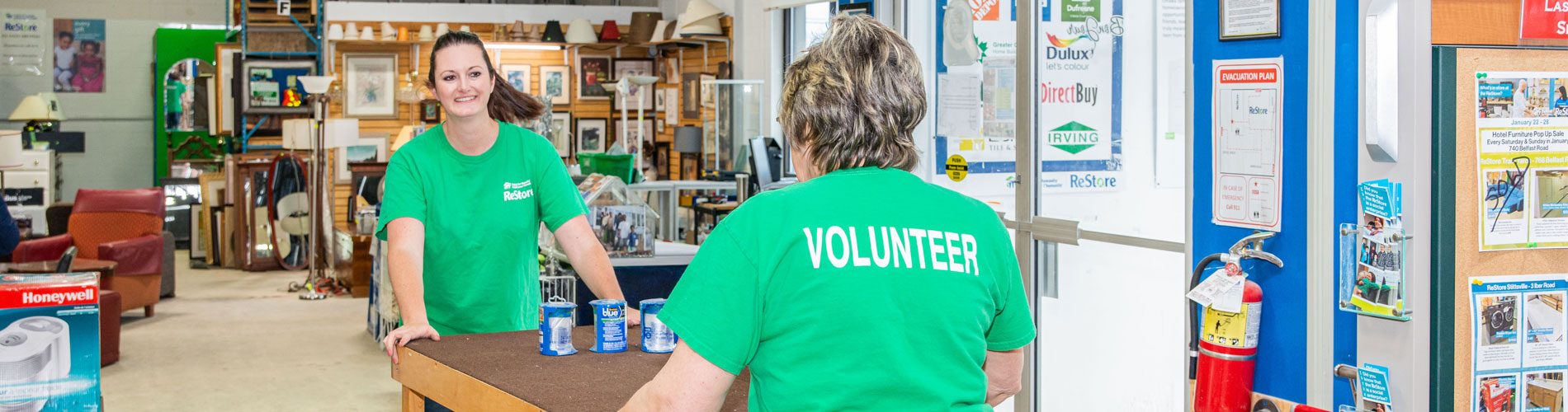 Two ReStore volunteers carrying a table.
