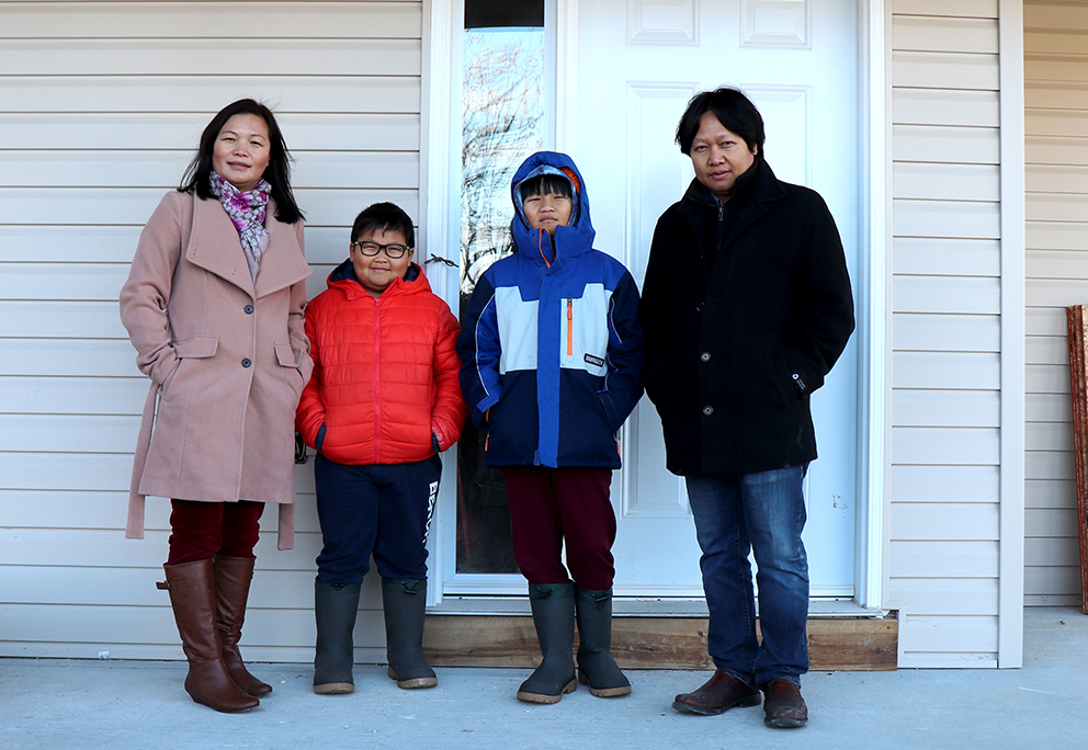 Habitat Partner Family Nilian and Tha and their two children standing in front of their Habitat home.