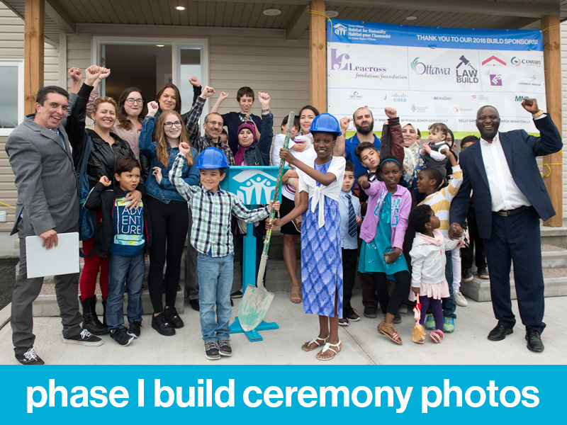 A large group of Habitat Partner families cheering during the Leacross Landing Phase I Build Ceremony. Text at bottom of image reads, "phase I build ceremony photos".