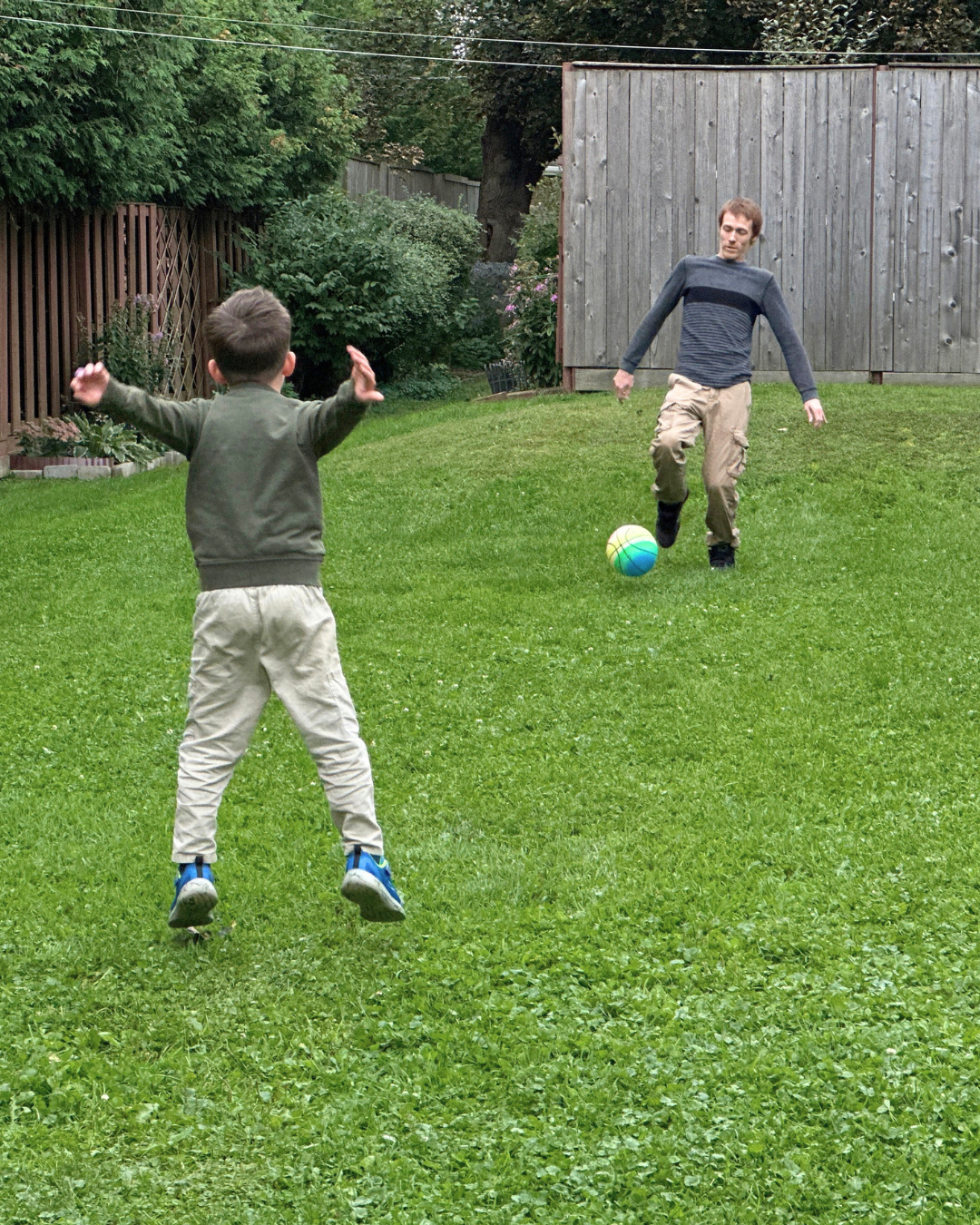 Kale plays kick ball with Dennis in a shared green space at their apartment.